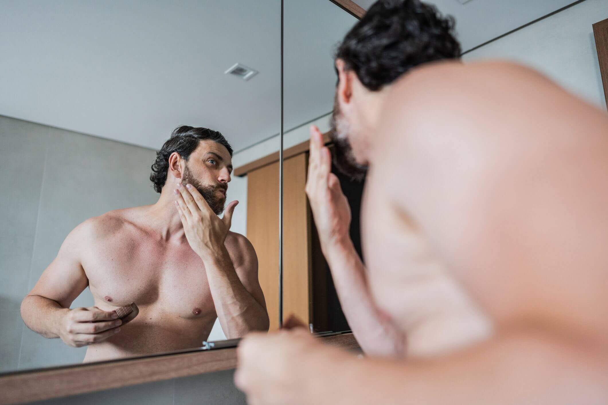 Man examining his facial skin in front of a bathroom mirror.