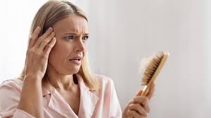 Worried woman examining hairbrush for hair loss.