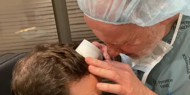 Person applying a medical patch to another person's scalp.