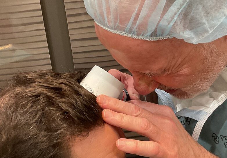 Professional applying a treatment or inspection to a person's scalp.