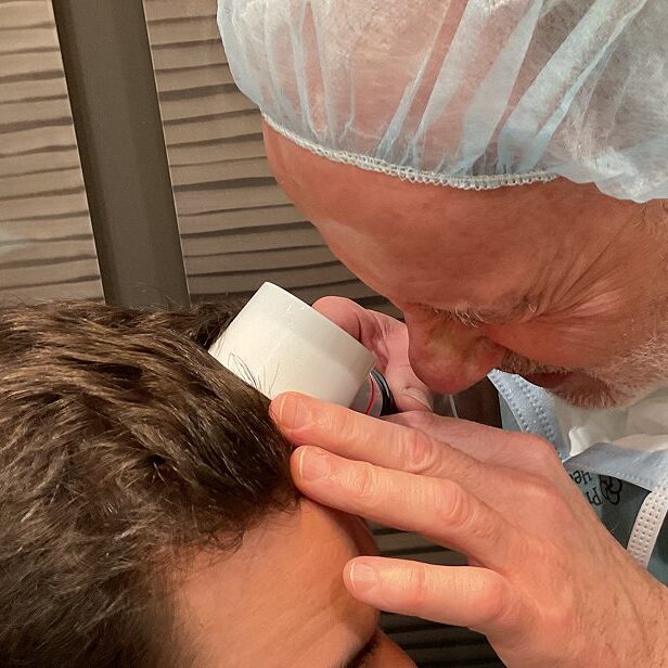 Professional applying a treatment or inspection to a person's scalp.