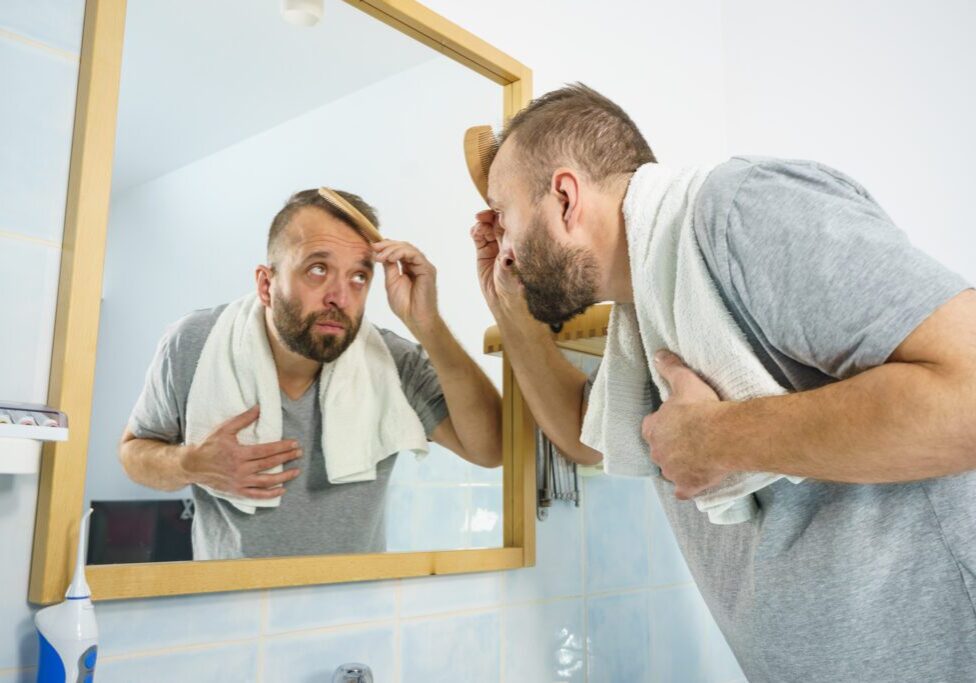 Man examining his face in the bathroom mirror.