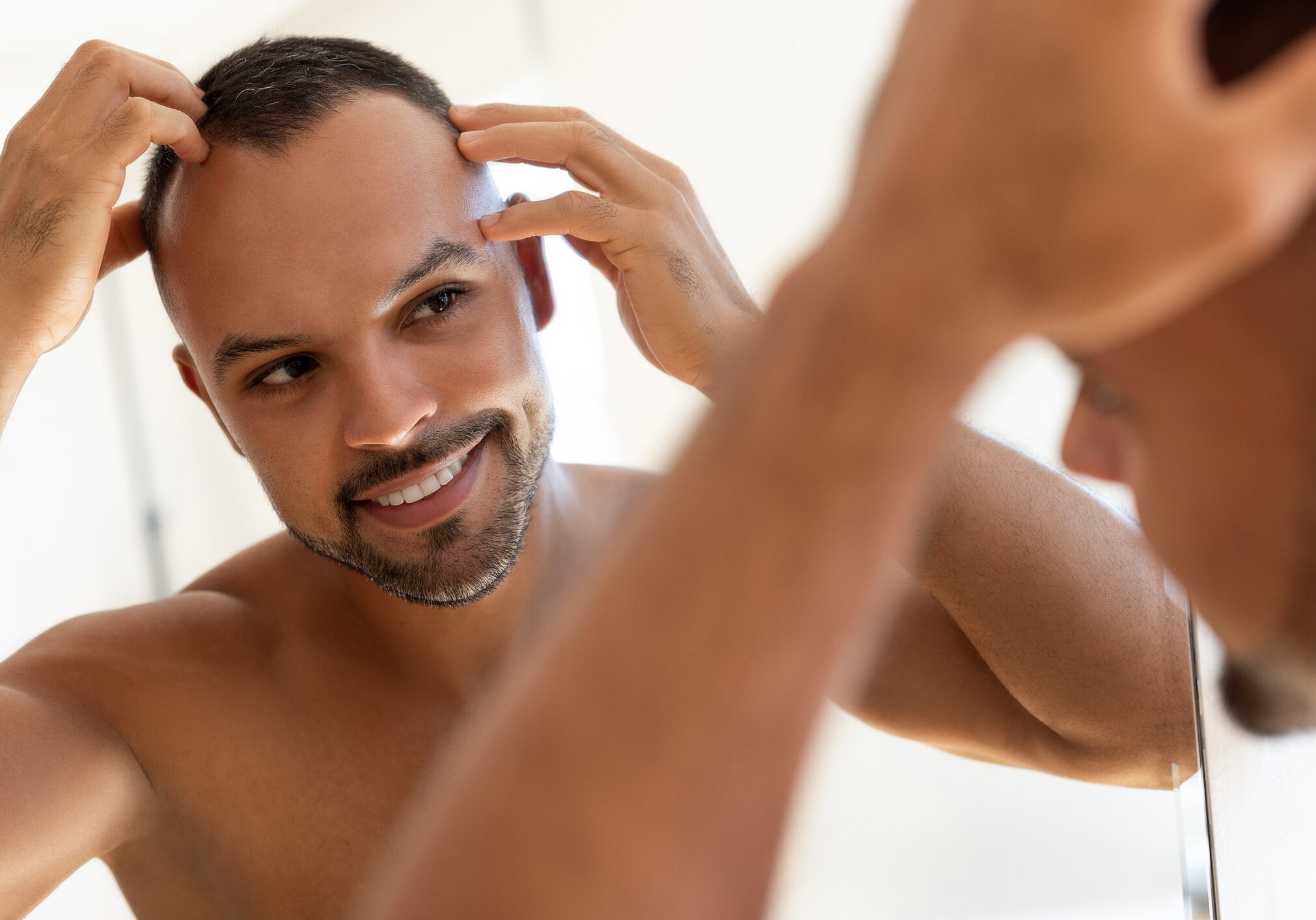 Man grooming his eyebrows in front of a mirror.