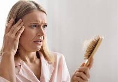 Worried woman examining hairbrush for hair loss.